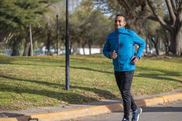 stock image Young Latino man runs by a public park.