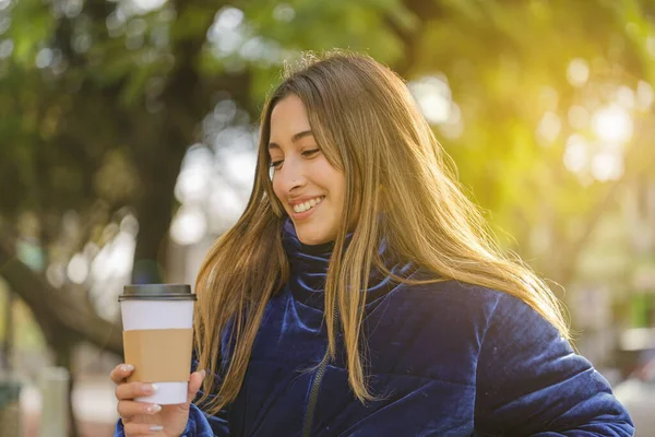 stock image Smiling beautiful latin girl drinking coffee on a public park bench.