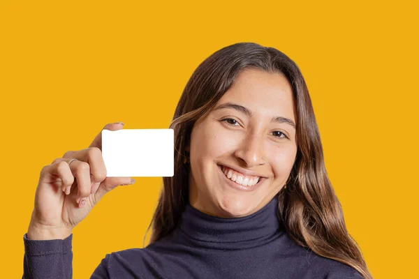 黄色い背景に隔離された空白のカードを示す笑顔のラティーナの少女の肖像画 — ストック写真