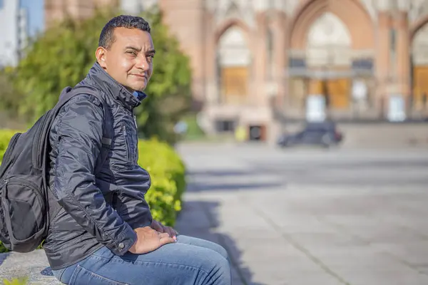 Halka açık bir parkta bankta oturan genç Latin bir adam..