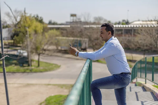 Latino Muž Košili Pomocí Mobilního Telefonu Opírající Zábradlí Pěší Most — Stock fotografie