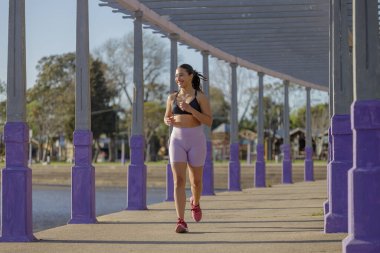 Halka açık bir parkta koşan gülümseyen Latin kız..