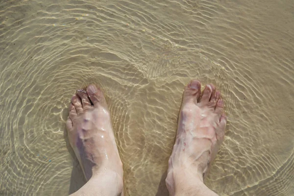 Top view of a man\'s feet in a swimming pool.