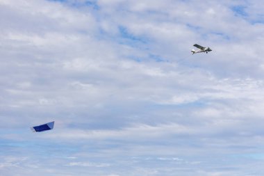 Boş reklam levhası olan küçük bir uçak bulutlu bir gökyüzü üzerinde uçuyor..