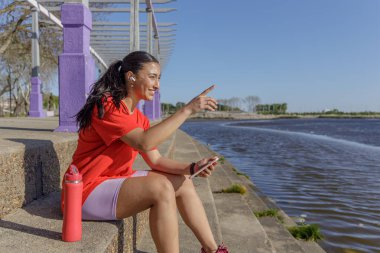 Nehrin kıyısında cep telefonunu kullanan gülümseyen Latin kız..