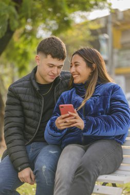 Latin bir kız ve beyaz bir oğlan halk parkında bir bankta oturuyorlar..