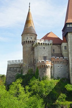 A fragment of the fairytale Hunyadi Castle in Romania: a view of the towers and bastions of the castle from the outside.    clipart
