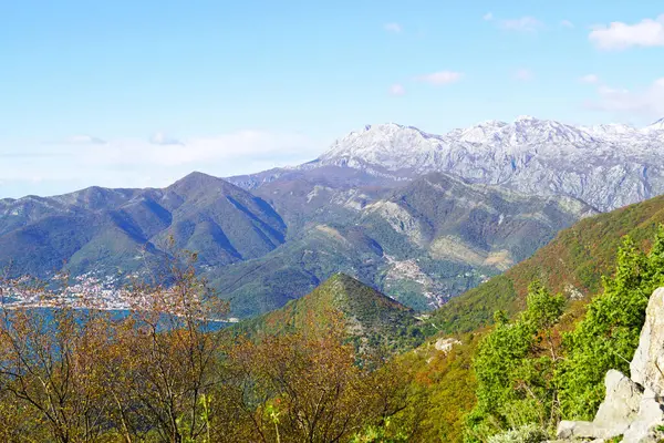 Contrasting landscape as the seasons change: autumn colors of Mount Vrmac and winter Orjen in the background (Montenegro). View of the hill with the Church of St. Vitus in the Bay of Kotor.