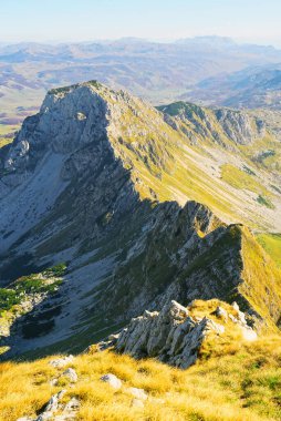 Karadağ 'ın Durmitor Ulusal Parkı' ndaki Ranisava Dağı 'nın en üst manzarası. Kıvrımlı bir dağ sırası, arka planda parlak sarı çimenler ve dağ siluetleri ile kaplı yamaçlar..