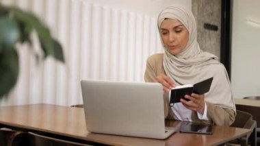 Serbest çalışan, eğitim gören, Webinar izleyen, video sohbeti yapan orta yaşlı Müslüman kadın. Ofis dışı iş, bağımsızlık, din, çeşitlilik, eşitlik kavramı