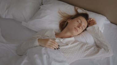 Tembel bir hafta sonu. Zarif pijamalı, uykulu, beyaz bir kadın uyanıyor. Yastığı açıyor, gülümsüyor ve yatakta geriniyor. Yeni gün tebrikleri ve sabah erkenden konforlu dairede eğlenmek.