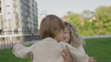 Anne ve kızı kucaklaşıyorlar, sevgi ve bağ kuruyorlar. Aile değerleri, bakım, birlikte iyi vakit geçirmek, mutluluk ve kasabanın arka bahçesinde eğlenmek