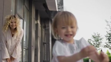 Küçük kız annesinden kaçıp gülüyor. Aile değerleri, bakım, birlikte iyi vakit geçirmek, mutluluk ve kasabanın arka bahçesinde eğlenmek 