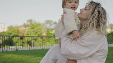 Anne ve kızı kucaklaşıyorlar, sevgi ve bağ kuruyorlar. Aile değerleri, bakım, birlikte iyi vakit geçirmek, mutluluk ve kasabanın arka bahçesinde eğlenmek
