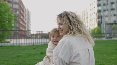 Anne ve kızı kucaklaşıyorlar, sevgi ve bağ kuruyorlar. Aile değerleri, bakım, birlikte iyi vakit geçirmek, mutluluk ve kasabanın arka bahçesinde eğlenmek