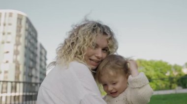 Anne ve kızı kucaklaşıyorlar, sevgi ve bağ kuruyorlar. Aile değerleri, bakım, birlikte iyi vakit geçirmek, mutluluk ve kasabanın arka bahçesinde eğlenmek
