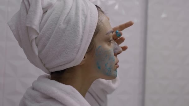 Nuori Viehättävä Nainen Pyyhe Kääritty Hänen Päänsä Soveltamalla Väri Kasvot — kuvapankkivideo