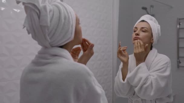年轻女人头上裹着毛巾 用洁肤泡沫洗脸 每天早上的日常事务 面部清洁 润肤及美容美发概念 — 图库视频影像