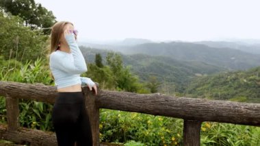 Young tourist woman enjoys the view from a wooden bridge high in the mountain designed for viewing the side from above. in the jungle. Vivid image of the mountain. Tourism destination. High quality 4k