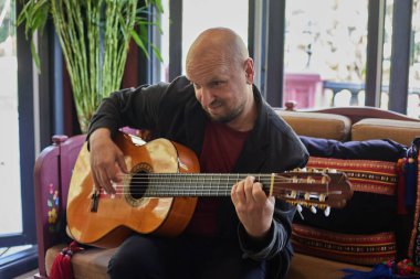 Akustik gitar çalan adam iç mekandaki etkinliğe müzik yeteneği katıyor. Yüksek kalite fotoğraf