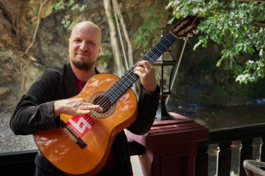 Erkek gitarist enstrümanını açık havada tutkuyla çalıyor. Yüksek kalite fotoğraf