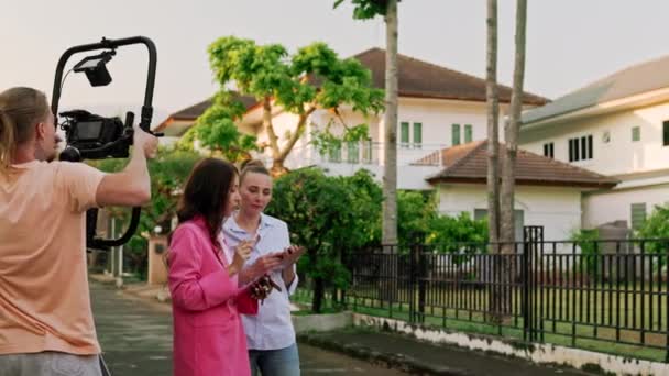 摄影师在两名妇女周围走动 在室外一间私人住宅的背景下对她们进行摄像拍摄 高质量的4K镜头 — 图库视频影像
