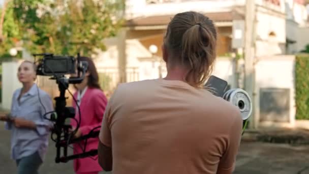 카메라맨은 크레인을 카메라를 사용하여 여성을 밖에서 촬영하고 있으며 배경에는 보인다 — 비디오