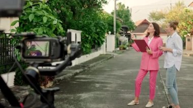 Arka planda özel bir ev olan bir kameraman, dışarıda iki kadını çekmek için vinç takılı bir kamera kullanıyor. Yüksek kalite 4k görüntü