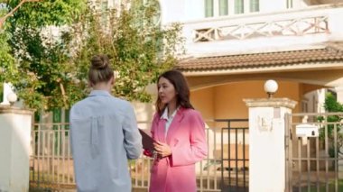Bir emlakçı ve müvekkili varlıklı bir mahalledeki evlerin önünde sohbet ediyorlar. Yüksek kalite 4k görüntü
