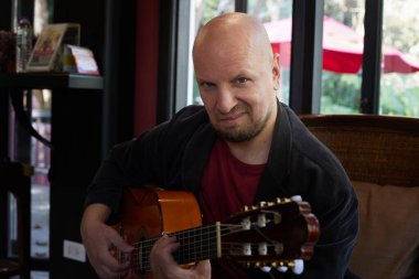 Eğlendirici erkek sanatçı yetenek ve ifade ile akustik gitar çalar. Yüksek kalite fotoğraf