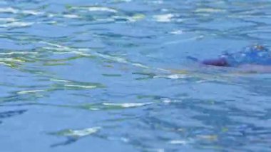 Havuzda gözlüklü profesyonel bir kadın yüzücünün yan görüntüsü. Bir kadın yüzücü su havuzuna dalıyor. Yakın çekim, yavaş çekim. Yüksek kalite 4k görüntü