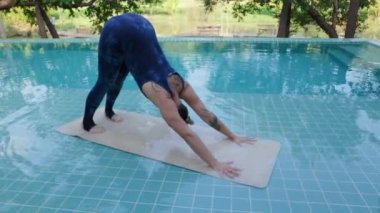 Havuz kenarındaki bu açık hava yoga seansının sakin atmosferi bu kişinin farkındalık ve iç huzura ulaşmasını sağlıyor. Yüksek kalite 4k görüntü