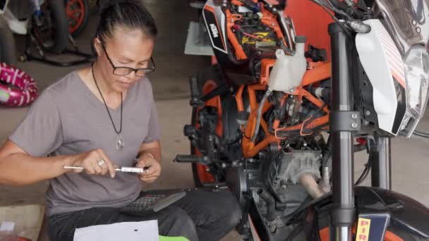 Gammal Asiatisk Kvinna Reparera Motorn Orange Motorcykel Verkstaden Högkvalitativ Film — Stockvideo