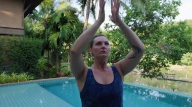 Havuz kenarındaki bu açık hava yoga seansının sakin atmosferi bu kişinin farkındalık ve iç huzura ulaşmasını sağlıyor. Yüksek kalite 4k görüntü