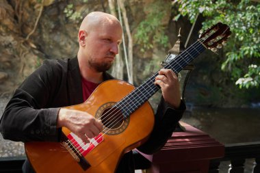 Akustik gitar tutan ve doğal ortamda pratik yapan bir adam. Yüksek kalite fotoğraf