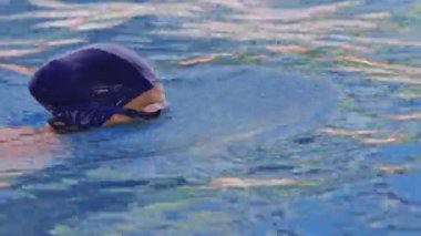 Havuzda gözlüklü profesyonel bir kadın yüzücünün yan görüntüsü. Bir kadın yüzücü su havuzuna dalıyor. Yakın çekim, yavaş çekim. Yüksek kalite 4k görüntü