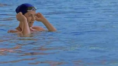 Havuzda gözlüklü profesyonel bir kadın yüzücünün yan görüntüsü. Bir kadın yüzücü su havuzuna dalıyor. Yakın çekim, yavaş çekim. Yüksek kalite 4k görüntü