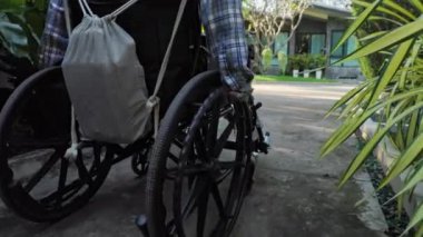 Otel parkında, tekerlekli sandalye kullanıcısı engelli insanların dahil edilme ve konaklama ihtiyacını vurgulayarak özgürce hareket eder. Yüksek kalite 4k görüntü