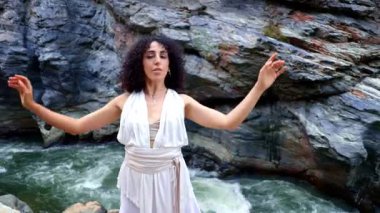 Bir Zarif Dansçı Dramatik Rocky Peyzajları Ortasında Şelaleden Nehir kenarındaki Duygu ve Hareketi İfade Ediyor. Yüksek kalite 4k görüntü