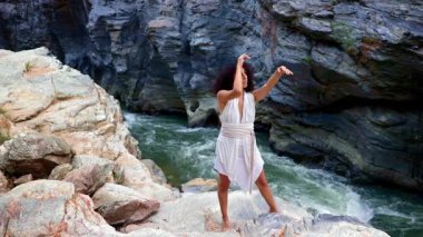 Akan Nehir ve Zarif Hareket: Bir Dansçı Doğanın Ortasında Sersemletici Vahşi Kayalarda Özgürlüğü İfade Ediyor. Yüksek kalite 4k görüntü