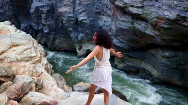 Rocky Riverbank Boyunca Huzurlu Yolculuk: Doğada Bir Kadının Zarif Hareketini Yakalamak. Yüksek kalite 4k görüntü