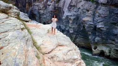 Sınırda Cesur Dans: Bir Kadın Heyecanlı Nehirlere Bakan Kayalık Kayalıklarda Zarifçe Zıplayarak Özgürlüğünü İfade Ediyor. Yüksek kalite 4k görüntü
