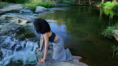 Waterside 'ın Serene Exploration by the Waterside: A Journey of Connection with Nature as Akan akıntıya uzanırken, etrafındaki sakinliği kucaklarken. Yüksek kalite 4k görüntü
