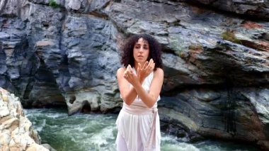 Akan Beyaz Giysili Serene Kadını Görkemli Doğal Kaya oluşumları ve Akan Nehir 'in ortasındaki Gökyüzüne uzanır, Doğanın Huzur ve Güzelliğini Kucaklar. Yüksek kalite 4k görüntü