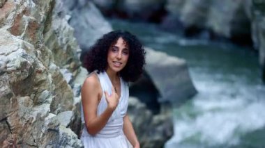 Suyun Huzurlu Anı: Beyaz Giyen Kadın Doğaya Yansıyor Kayalık Arazi ve Akan Sular Arasında Kucaklıyor. Yüksek kalite 4k görüntü