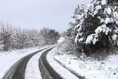    Kışın kar mevsiminde, karlı manzarayla kaplı, boş bir yol manzarası. Kaygan kış yolundan sağa dön. Kasvetli bir kış günü. Ukrayna.