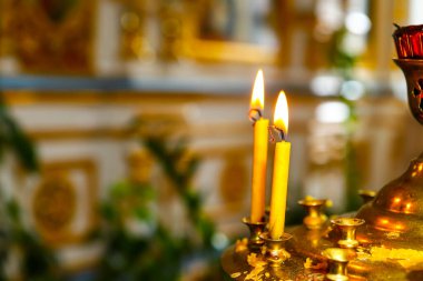 Ortodoks kilisesinin önünde mum yakan bir şamdan. Ortodoksluk kavramı. Yumuşak ışık, seçici odak.