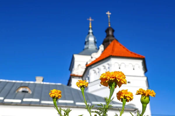 古代正教会の修道院の円錐形のドームは ウクライナ西部の深い青い空に対して十字架で修復されました 黄色いマリーゴールドの花 正統主義とキリスト教信仰の概念 — ストック写真