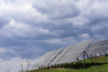 Karanlık fırtınalı bir gökyüzünün arka planındaki güneş panelleri. Güneş enerjisi santrali. Güneş çiftliği. Alternatif ekolojik elektrik kaynağı.
