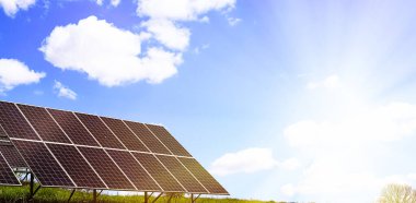 Açık havada çalışan bir güneş pili tesisi. Doymuş mavi bulutlu gökyüzünün arka planında fotoelektrik piller var. Güneş panelleri. Ekoloji, alternatif enerji kavramı